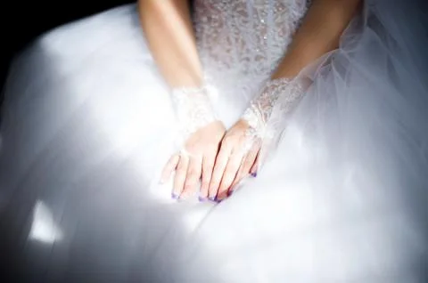 The bride put her hands on her knees and she is illuminated by a ray of light Stock Photos