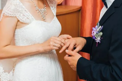 Bride puts a gold wedding ring on the finger of the groom Stock Photos