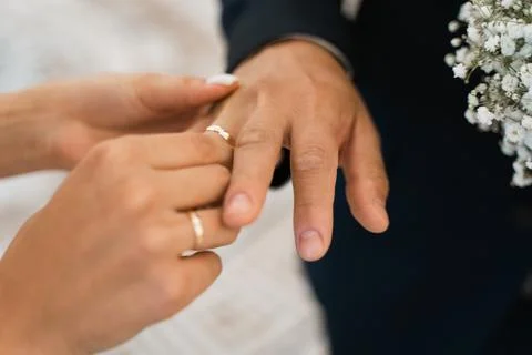 Bride puts gold wedding ring on groom's finger Stock Photos