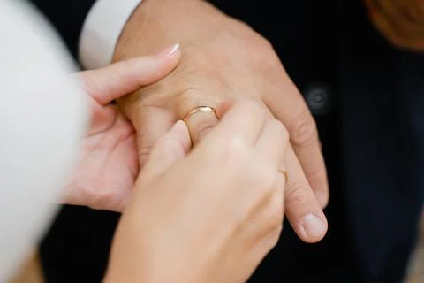 Bride puts gold wedding ring on groom's finger Stock Photos