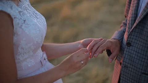 The bride puts the ring on the finger of the groom. Wedding ceremony at sunset. Stockbeeldmateriaal 82844224
