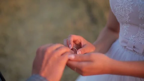 The bride puts the ring on the finger of the groom. Wedding ceremony at sunset. Video stock 82844256