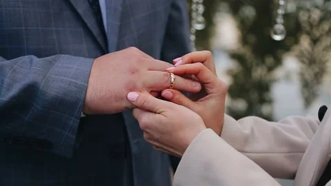 The bride puts the wedding ring on the groom's finger near the wedding arch Stock Footage 154893412