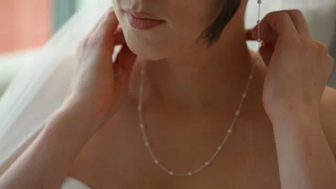 Bride putting on a delicate pearl necklace while getting ready, capturing an Stock Footage 324243433