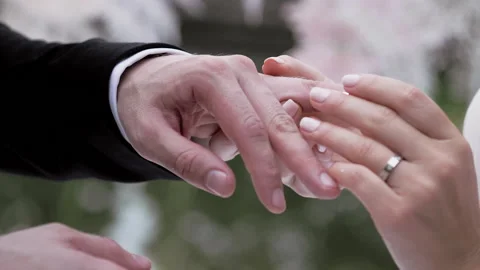 Bride putting wedding ring on brides finger close up summer day no face slow.  Stock Footage 131653606
