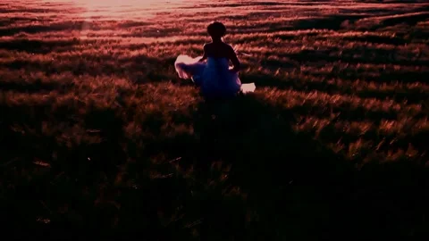 Bride running through a high grain field at sunset Stock Footage 157611693