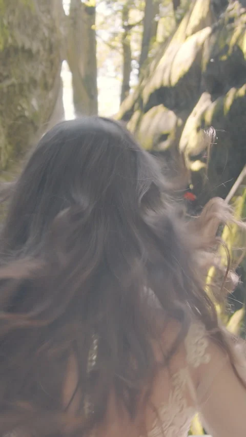 Bride runs between cliffs under golden sun. Her white dress glows in the Stock Footage 313630799