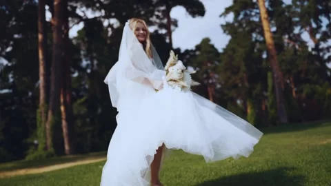 The bride runs on the lawn, looking back at the camera Stock Footage 163971424