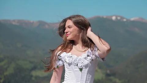 Bride shields her face from bright sun in a windy mountain portrait, Romantic Vidéo 344419231