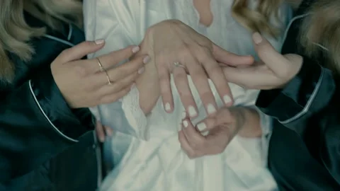 A bride shows the ring with a diamond on her finger to two of her friends. Stock Footage 230012246