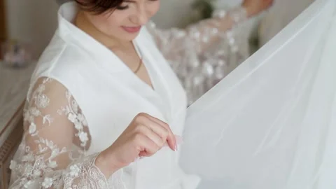 Bride In Silk Dressing Gown Holding And Admiring Her Beautiful Wedding Dress Stock Footage 234086454