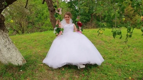 The bride sits on a beautiful swing Stock Footage 75025126