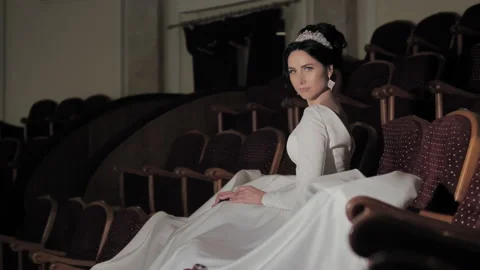 The bride sits in an empty auditorium with a fluffy dress spread. Stock Footage 151773522