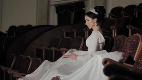 A bride sits in an empty theater auditorium with a fluffy dress spread. 库存影片 151773451