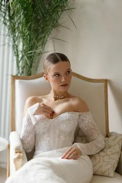 Bride sitting on couch wearing elegant wedding dress Stock Photos
