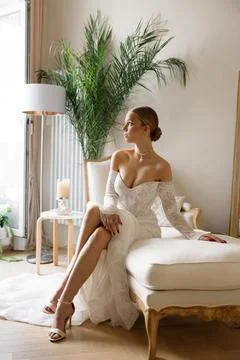 Bride sitting on couch wearing elegant wedding dress Foto stock