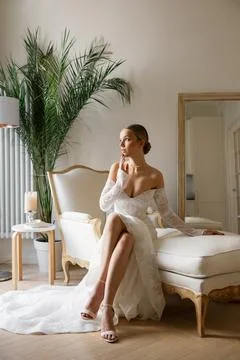 Bride sitting on couch wearing elegant wedding dress Stock Photos