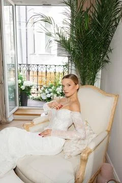 Bride sitting on couch wearing elegant wedding dress Stock Photos