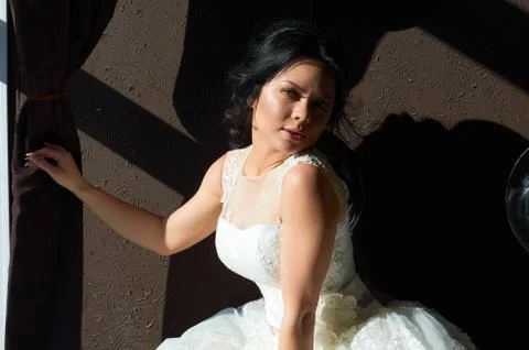 The bride is sitting on the sofa and looking out the window.sun ray.wedding g Stock Photos