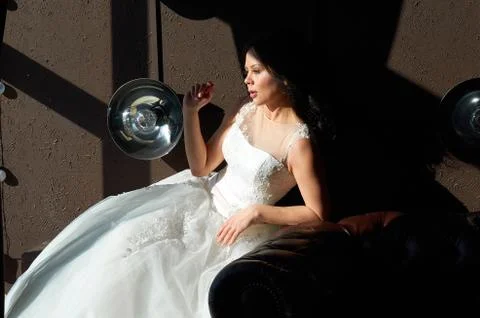The bride is sitting on the sofa and looking out the window.sun ray.wedding g Stock Photos