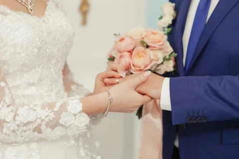 The bride smiles joyfully when she puts the golden ring on her husbands finge Stock Photos