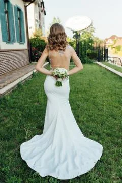 The bride socks her back to the frame and holds a bouquet of colorful flowers. Stock Photos