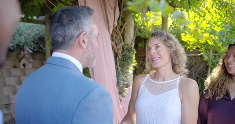 Bride speaking during wedding vows under pergola pink drapery, groom stepping Stock Footage 336536471
