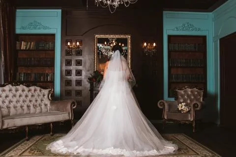 The bride is standing in front of a mirror in a beautiful room. Stock Photos