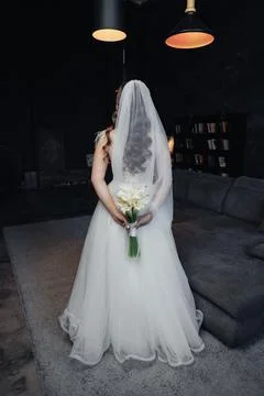 Bride stands with back turned, veil flowing gently Foto stock