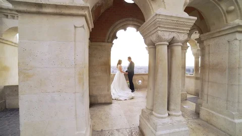 Bride stands on balcony of old castle, on background. old town and river Stock Footage 129336614