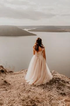 Bride stands on a cliff against the background of the river and islands Stock Photos