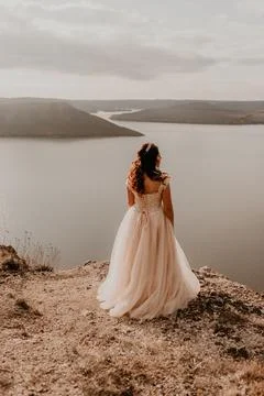 Bride stands on a cliff against the background of the river and islands Stock Photos