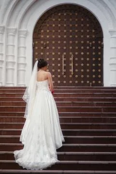 The bride stands with her back on the steps against the background of the door Stock Photos
