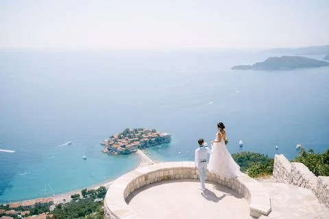 The bride stands on the parapet of the observation deck overlooking the island 库存照片