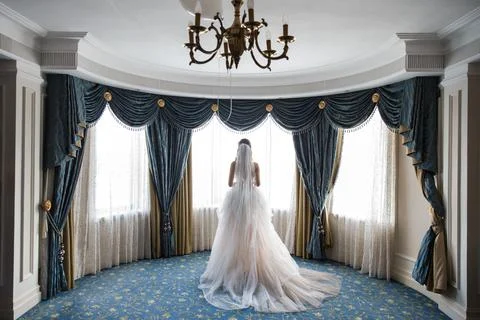 The bride stands in a room in front of the windows Stock Photos