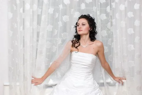 Bride stands by the window Stock Photos