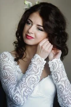 Bride stays thoughtfully while putting on her earrings Stock Photos