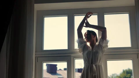 Bride stretching by the window in morning light, elegant moment as she prepares Stock Footage 292149347