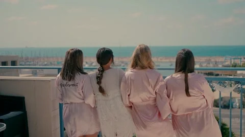 A bride with three girlfriends dressed in satin robes dance on a balcony. Video stock 242016366