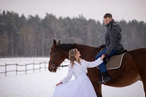 Bride Touching Groom Hand While He Rides Horse Stock Photos