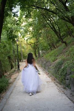 Bride walking down a forest path alone with high heels in her hands Foto stock