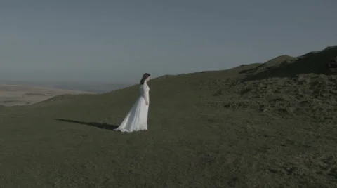 Bride walking up windy hill Stock Footage 38837985