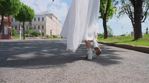 A bride walks down the road, her dress unfolding in slow motion. Stock Footage 329092361