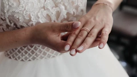 The bride wears wedding ring on her finger before the wedding. Bride in weddress Stock Footage 131339337