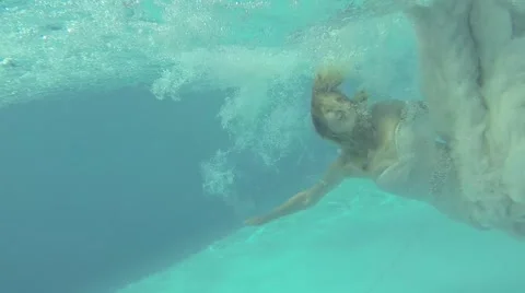 Bride in wedding dress jumping in pool swimming Stock Footage 44019532