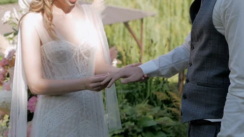 A bride at a wedding puts a ring on her fiance against the background of an arch Stock Footage 127836294
