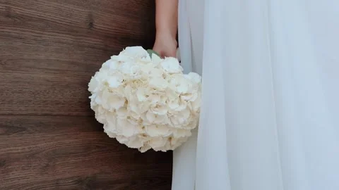 A bride with a wedding ring on her hand strokes and admires her wedding bouquet Stock Footage 252196615