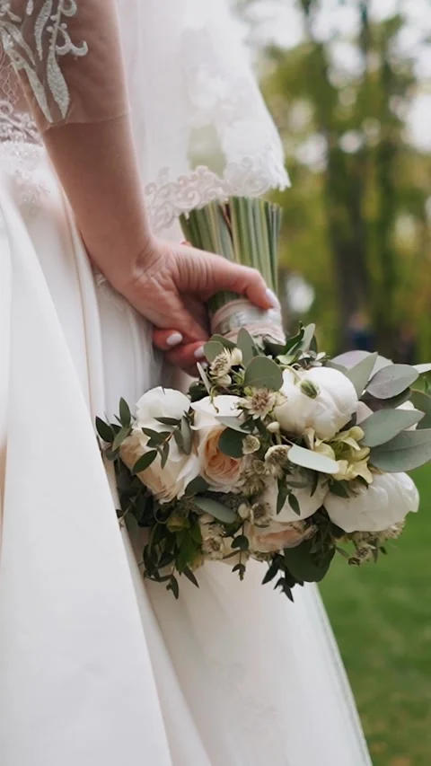 A bride with a wedding ring on her hand strokes and admires her wedding bouquet Stock Footage 252267658