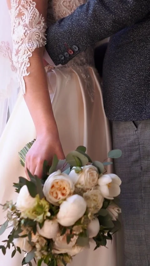 A bride with a wedding ring on her hand strokes and admires her wedding bouquet Stock Footage 252267670