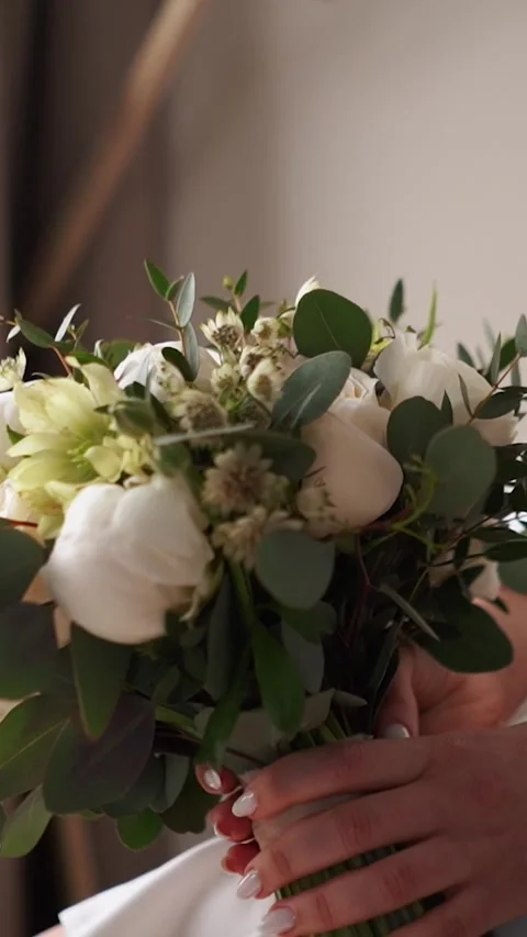 A bride with a wedding ring on her hand strokes and admires her wedding bouquet Stock Footage 252267686